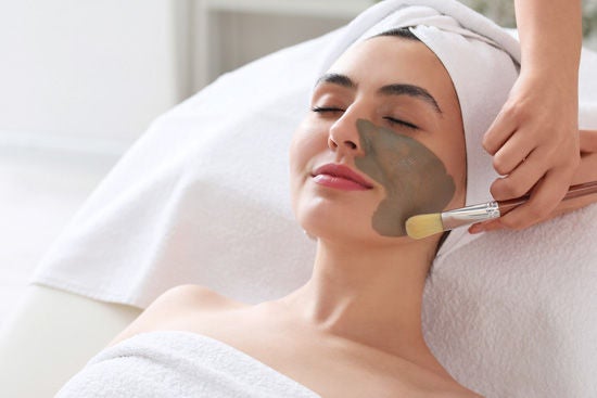 kozmetolog genç kişiye kil maskesi uyguluyor