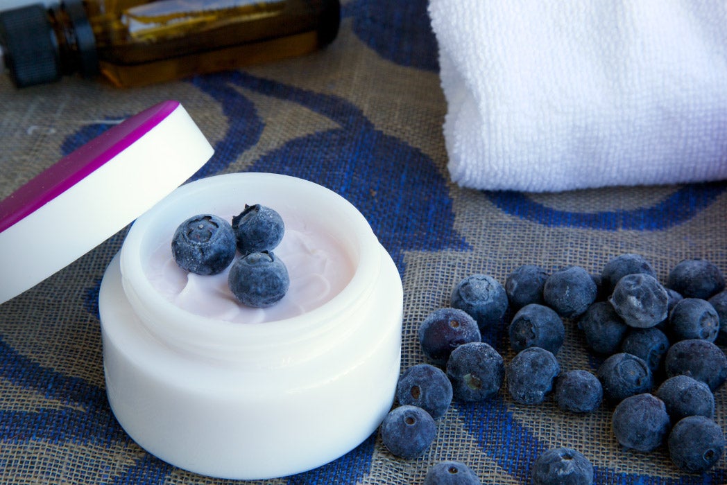 yanında bir koku kavanozu olan ahşap yüzeyde yaban mersinleri