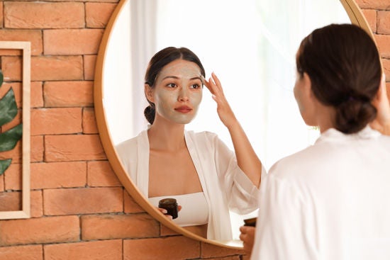 güzel Asyalı kadın kil maskesi uyguluyor