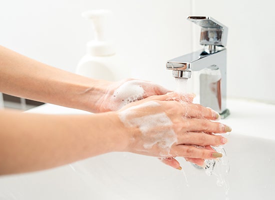 Kadın ellerini su ve sabunla yıkıyor
