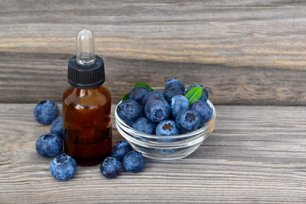 yanında bir koku kavanozu olan ahşap yüzeyde yaban mersinleri