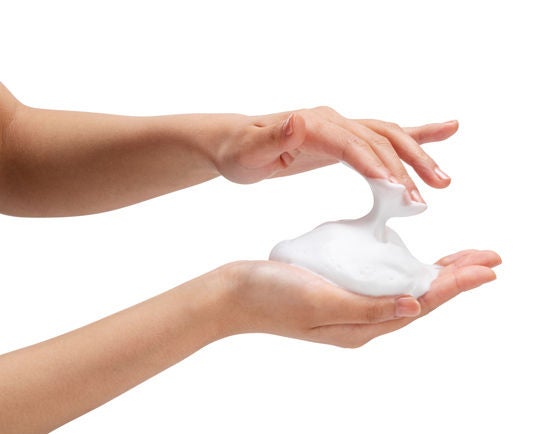 beyazın üzerinde kadın eli sabun köpükleri