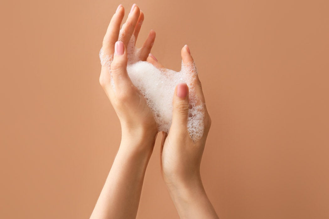 turuncu bir arka planda sabunlu kız elleri